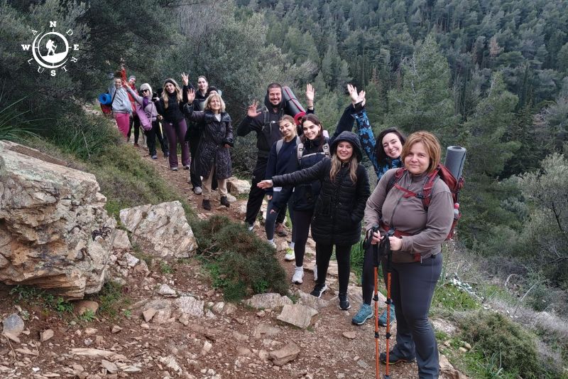 Ομάδα πεζοπόρων σε βραχώδες μονοπάτι με θέα στις δασωμένες πλαγιές του Υμηττού